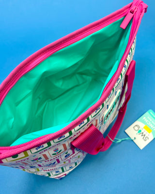 An open tote bag with a white exterior covered in colorful tennis-themed graphics, a bright pink zipper and handle, and a mint green interior, shown on a blue background with a tag attached.