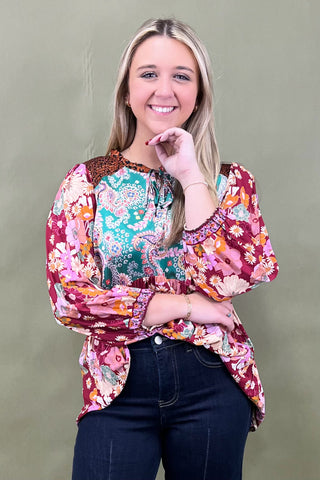 Woman wearing a colorful floral blouse against a plain background