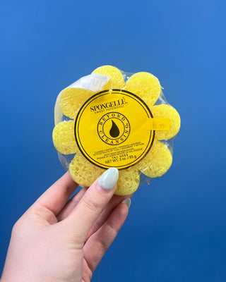 Spongellé Flower Body Wash Infused Buffer available in multiple fragrances, featuring a flower-shaped cleansing sponge infused with body wash and a convenient hanging ribbon.