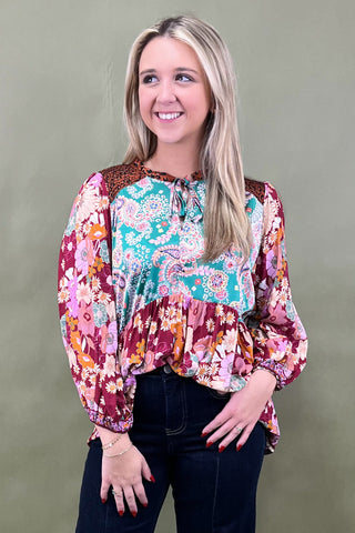 Woman wearing a colorful floral blouse against a plain background