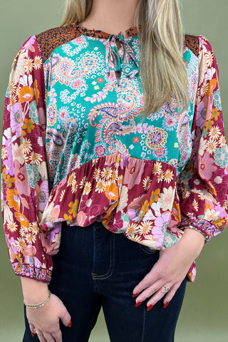 Woman wearing a colorful floral blouse with a green background
