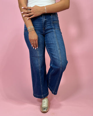 Person wearing blue jeans on a pink background