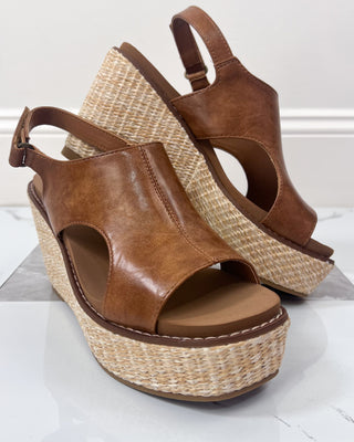 Brown wedge sandals with woven sole on a white surface