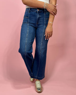 Person wearing blue jeans on a pink background