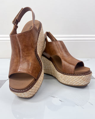 Brown wedge sandals with espadrille sole on a white background