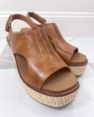 Brown open-toe sandals with woven sole on a white background