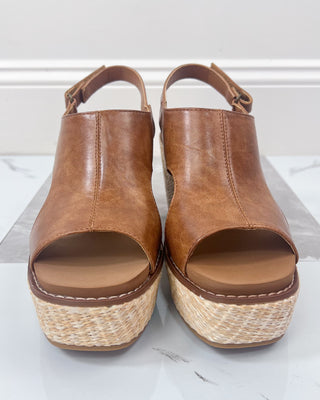 Pair of brown open-toe sandals with woven sole on a white background