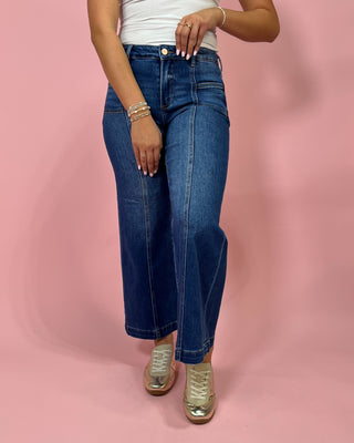 Person wearing blue jeans on a pink background