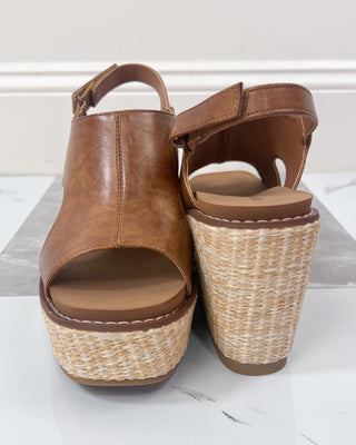 Brown wedge sandals with woven sole on a white background