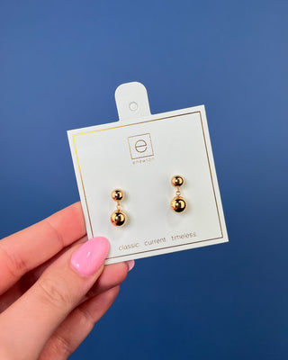 eNewton Classic 8mm Ball Drop Stud Earrings in classic gold featuring polished gold ball studs with suspended 8mm gold ball drops and secure post backs displayed on an eNewton jewelry card.