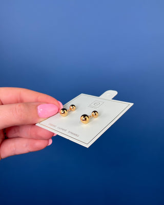 eNewton Classic 8mm Ball Drop Stud Earrings in classic gold featuring polished gold ball studs with suspended 8mm gold ball drops and secure post backs displayed on an eNewton jewelry card.
