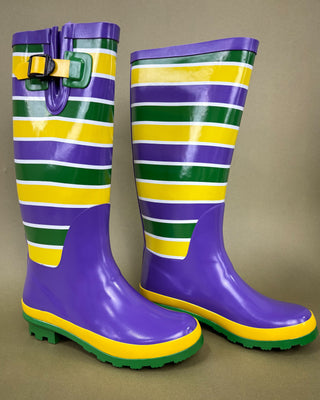 Pair of purple, green, and yellow striped rain boots on a beige background