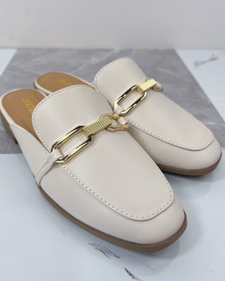 Pair of white loafers with gold buckles on a marble surface