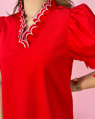 Red dress with intricate white detailing on a pink background