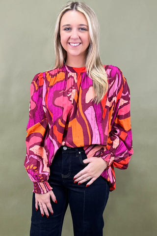 Woman wearing a colorful patterned blouse against a plain background