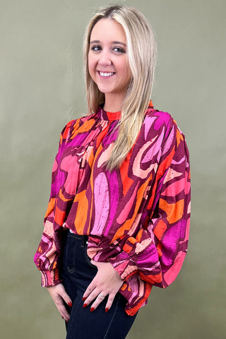 Woman wearing a colorful patterned blouse against a plain background