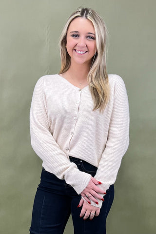 Woman wearing a cream cardigan against a green background