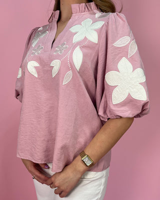 Pink blouse with white floral patterns on a pink background