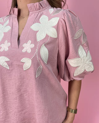 Pink dress with white floral embroidery on a pink background