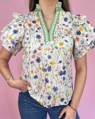 Woman wearing a floral blouse with a green collar against a pink background
