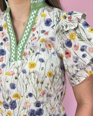 Floral-patterned blouse with green accents on a pink background