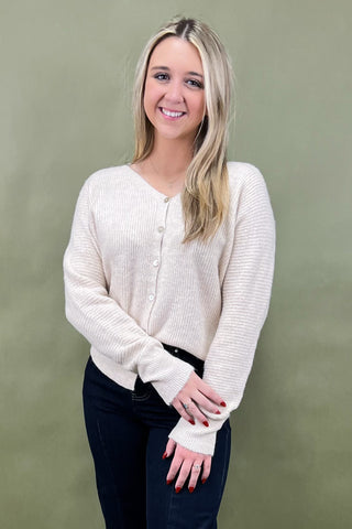 Woman wearing a cream sweater against a green background