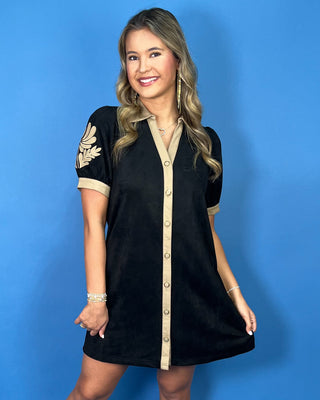 Black mini dress with tan contrast trim, button-front design, puff sleeves, and embroidered floral detail on the sleeves.