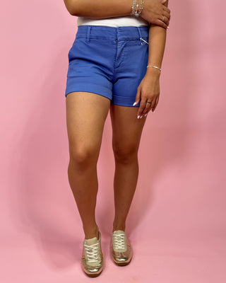 Person wearing blue shorts on a pink background