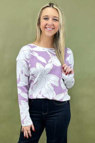 Woman wearing a purple floral sweater against a green background