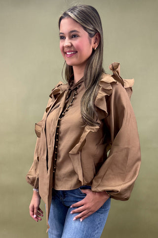 Woman wearing a brown ruffled blouse with a green background
