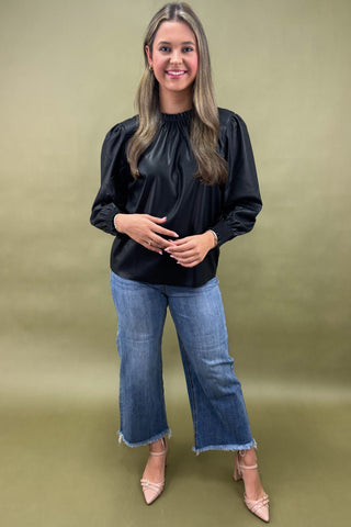 Woman wearing a black top and blue jeans on a green background