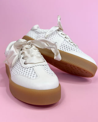 White sneakers with brown soles on a pink background
