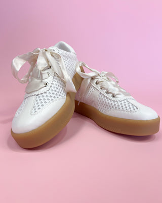 White sneakers with brown soles on a pink background