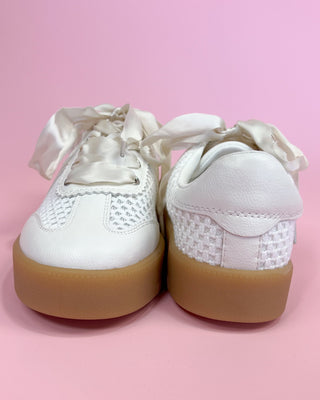 White sneakers with brown soles on a pink background