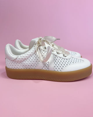 White sneakers with a patterned sole on a pink background