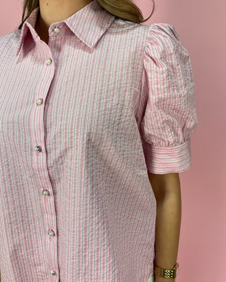 Pink and white striped shirt worn by a mannequin against a pink background