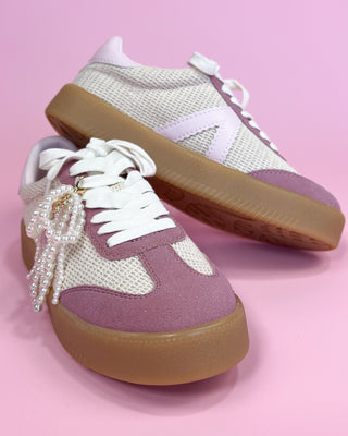 Pair of sneakers with a pearl detail on a pink background