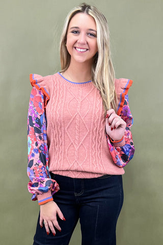 Woman wearing a pink sweater with colorful sleeves against a green background