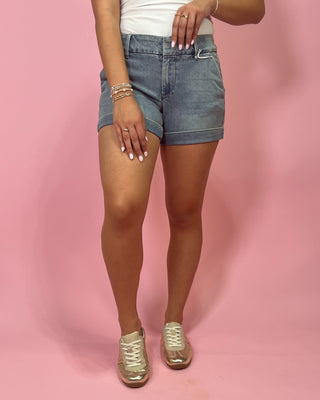 Person wearing denim shorts on a pink background