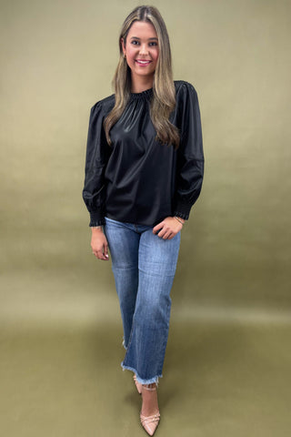 Woman wearing a black top and blue jeans on a beige background