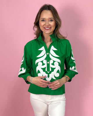Woman wearing a green shirt with white patterns against a pink background