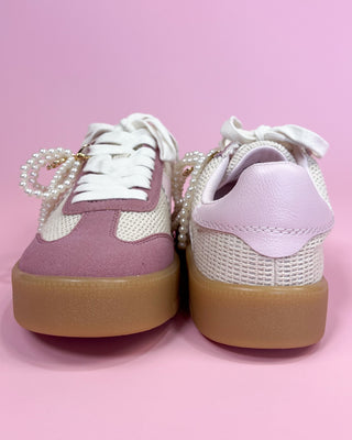 Pair of pink and white sneakers with brown soles on a pink background