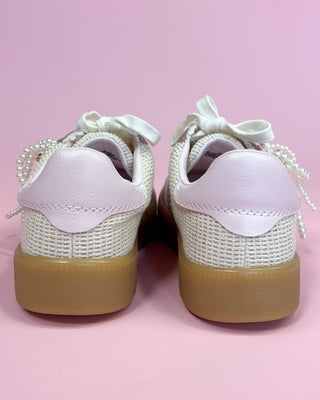 White sneakers with brown soles on a pink background