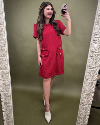 Woman taking a mirror selfie wearing a red dress with a patterned background