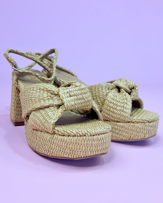 Pair of woven sandals on a light purple background