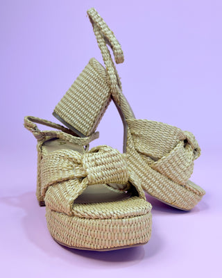 Pair of woven sandals on a light purple background