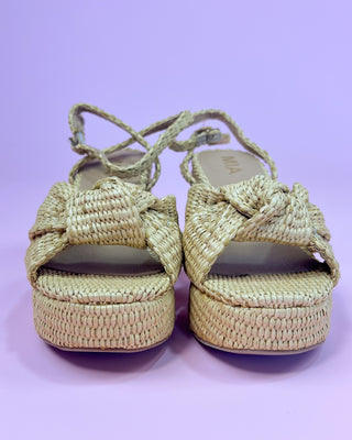 Pair of woven sandals on a light purple background