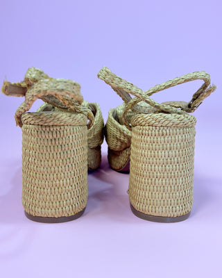 Woven sandals with rope straps on a light purple background