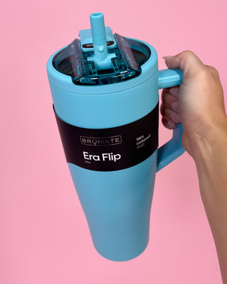 Blue travel mug with handle and straw on a pink background