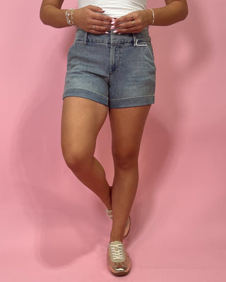 Person wearing blue denim shorts on a pink background